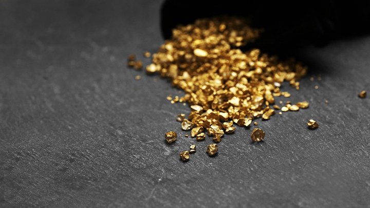 A pouch with scattered gold nugget grains, on cement background