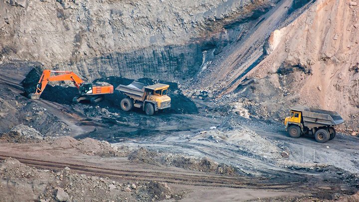 Crawler excavator and dump trucks are working in a quarry
