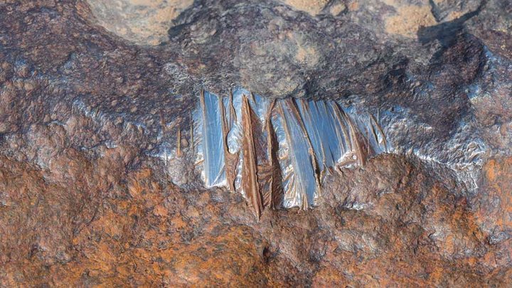 Polished glowing surface of meteorite composed by high density heavy metals mostly iron and nickel.