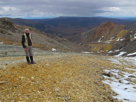 The Company’s Exploration Manager at Dry Creek West looking west along strike within the footwall alteration zone, with Red Mountain in the background.